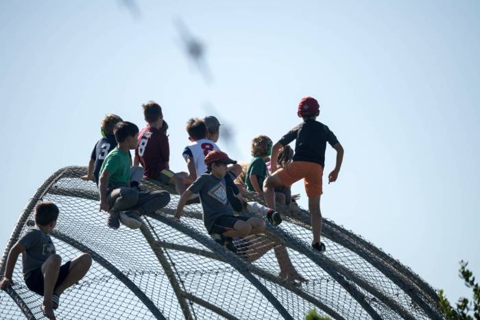 Kids on a baseball backstop watching the Blue Angels