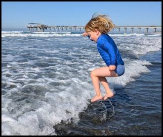 Jumping over wave white water at beach